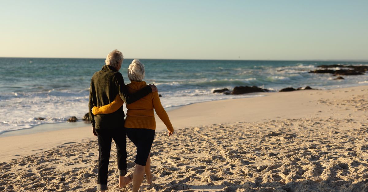 An older couple walking together on a beach — good cardiometabolic health means more active, independent years