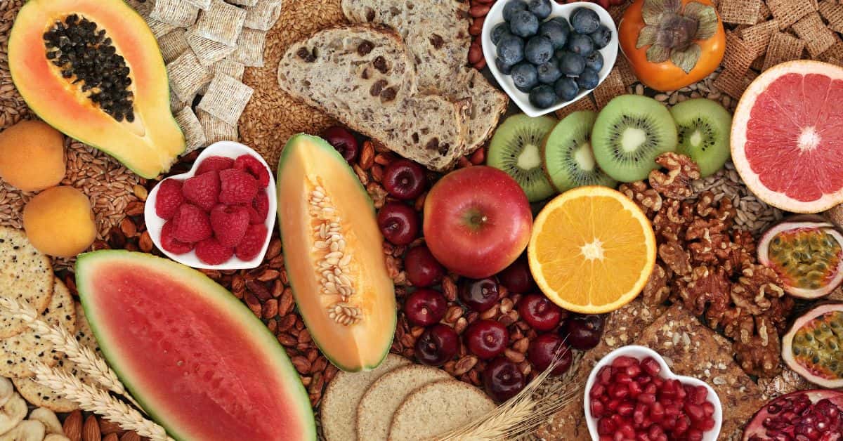 longevity-tips-fibre-whole-foods-stressfreelongevity Colourful spread of high-fibre foods including fruit, whole grains, nuts, and seeds