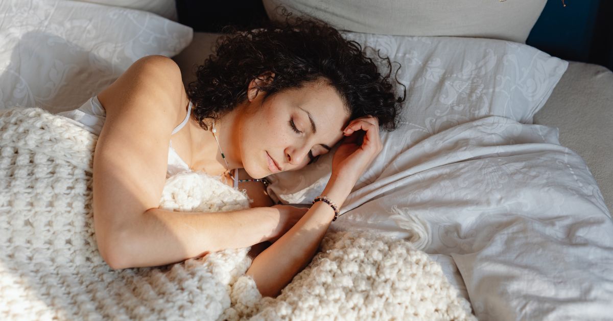 longevity-tips-sleep-stressfreelongevity Woman sleeping peacefully in warm light — prioritising sleep for longevity