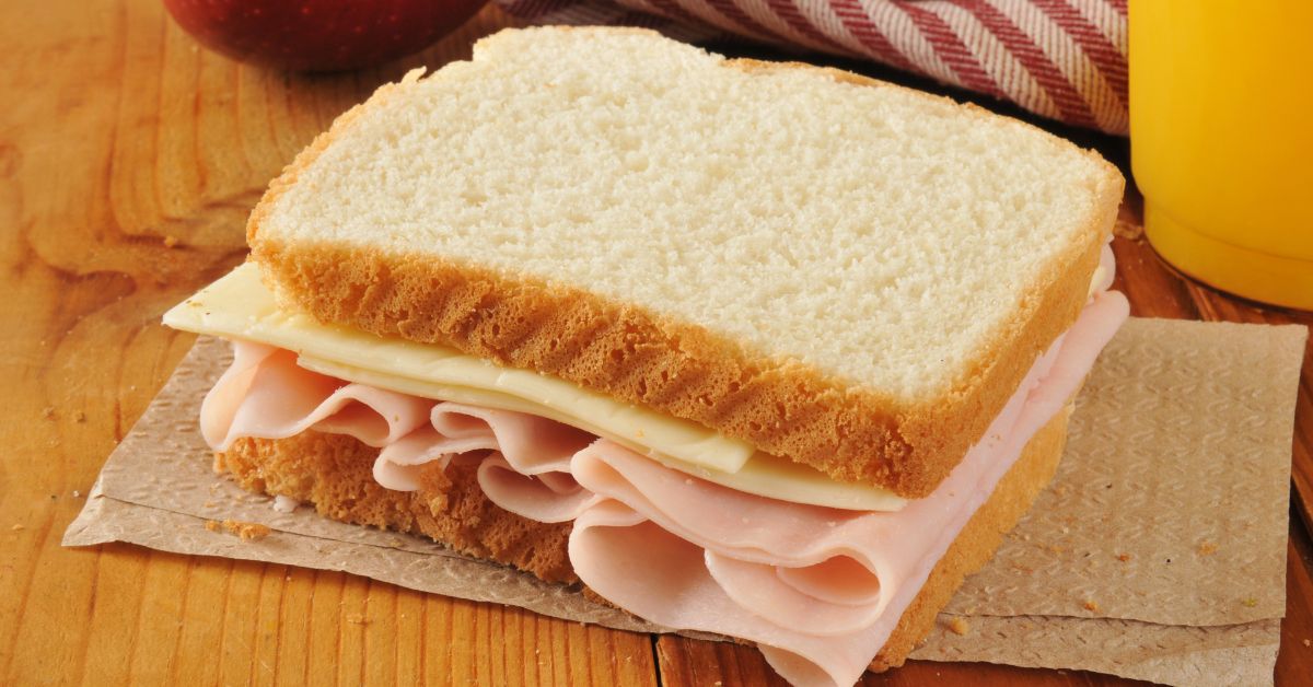 white-bread-sandwich-blood-sugar-stressfreelongevity White bread sandwich with processed meat, the type of refined carbohydrate meal that causes blood sugar spikes