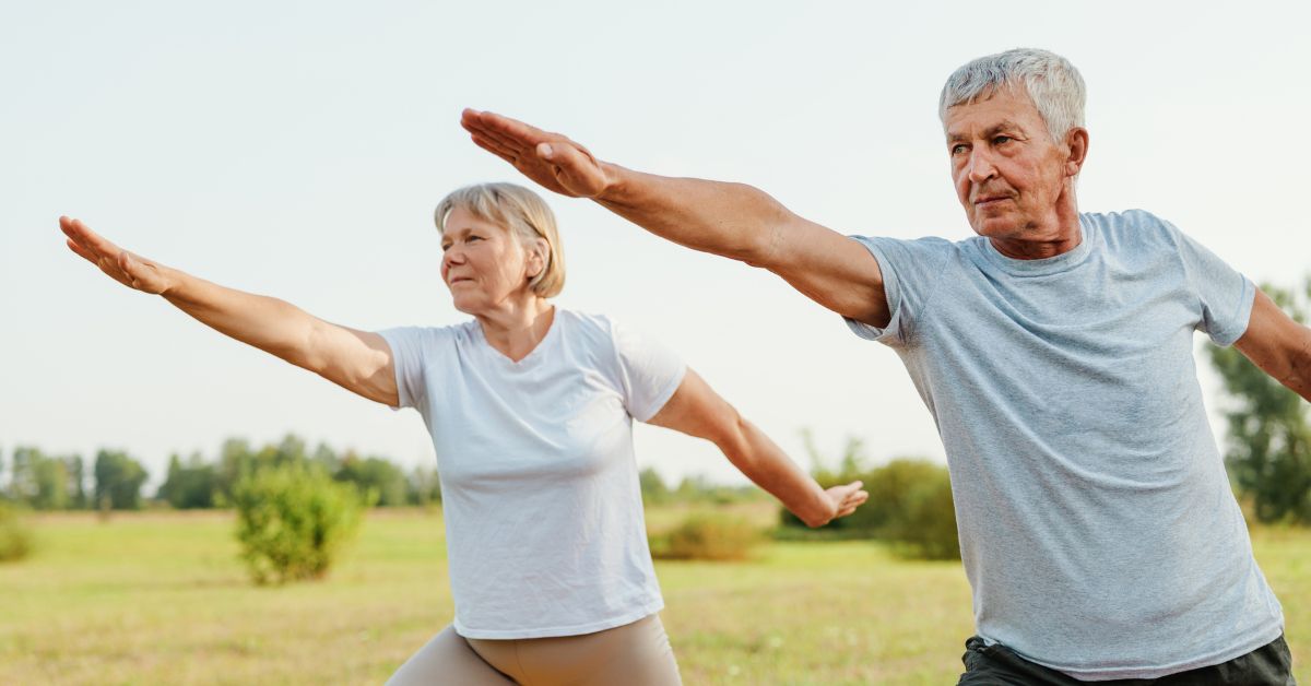 Older couple doing balance exercises outdoors in a field