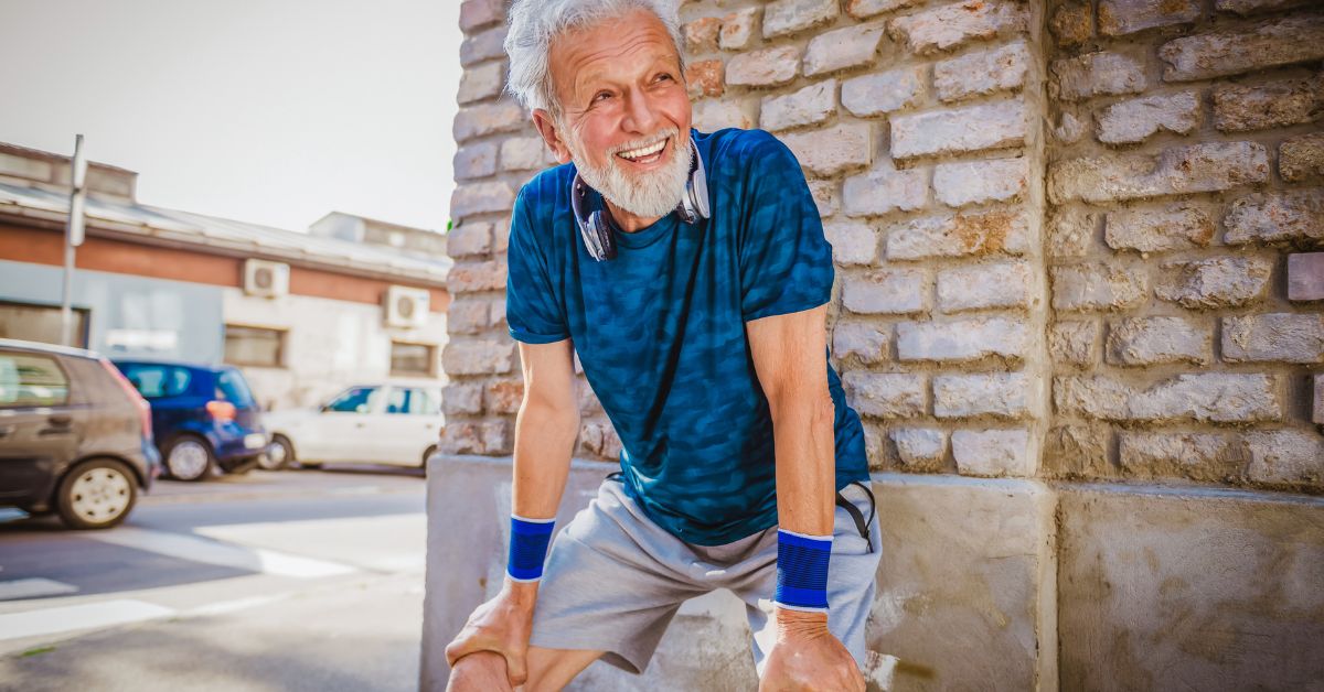 Older man smiling and catching his breath after a run outdoors