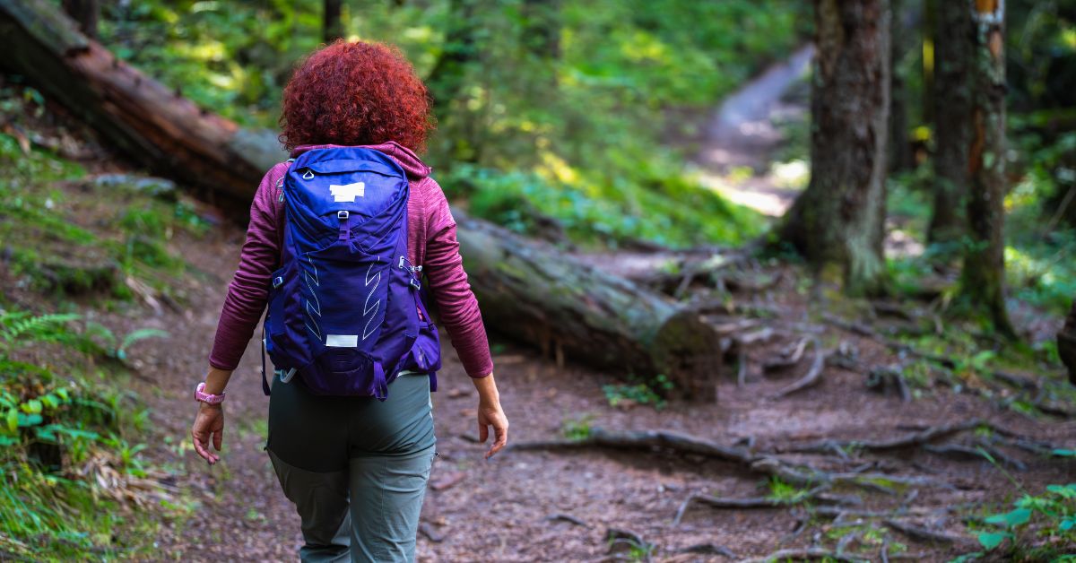 Woman walking along a forest trail with a backpack