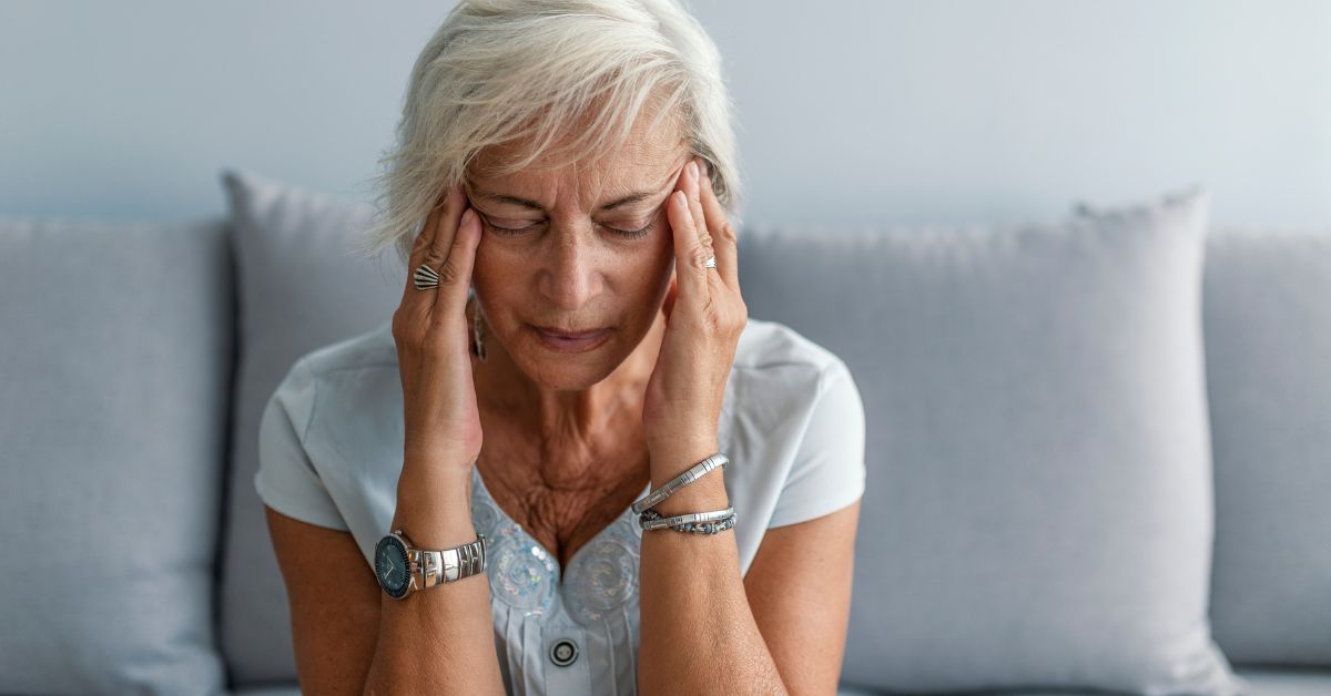 Woman over 40 experiencing a migraine, holding her temples