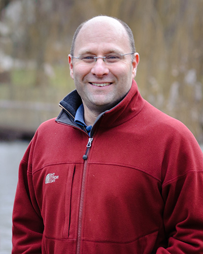 Professor Alistair Boxall wearing a red fleece standing in an outdoor scene by a river