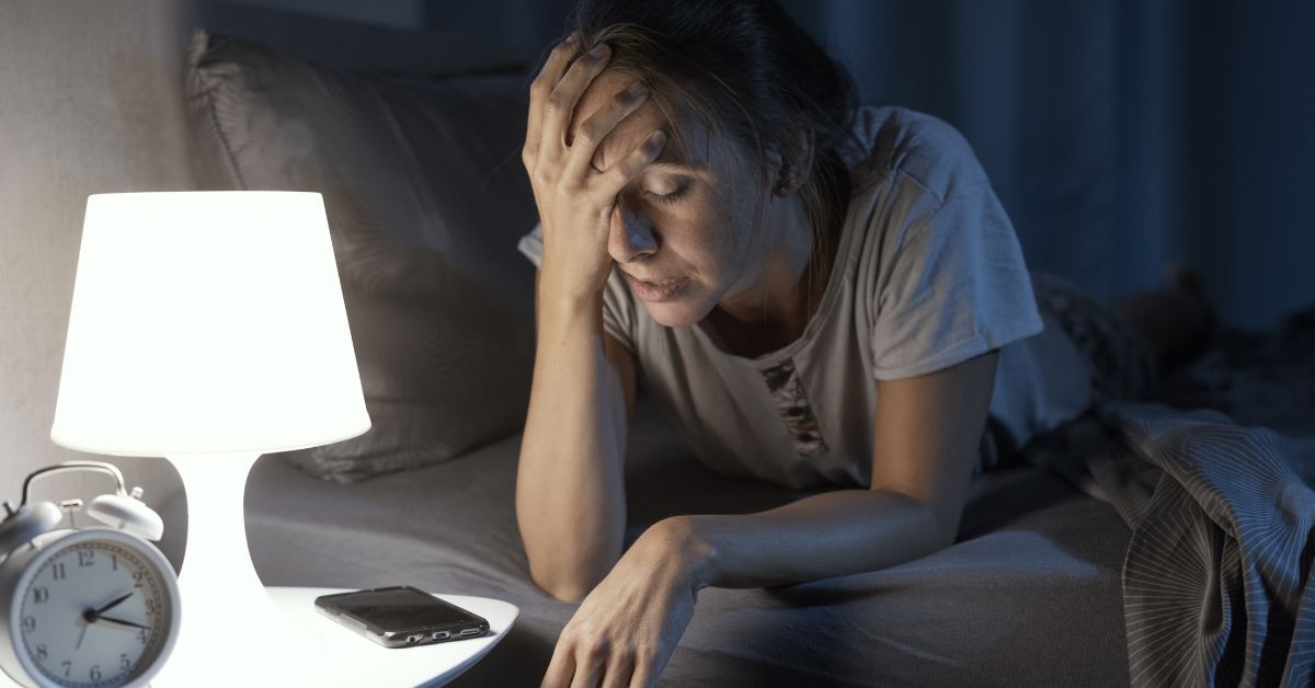 Woman lying awake in bed at night unable to sleep when stressed