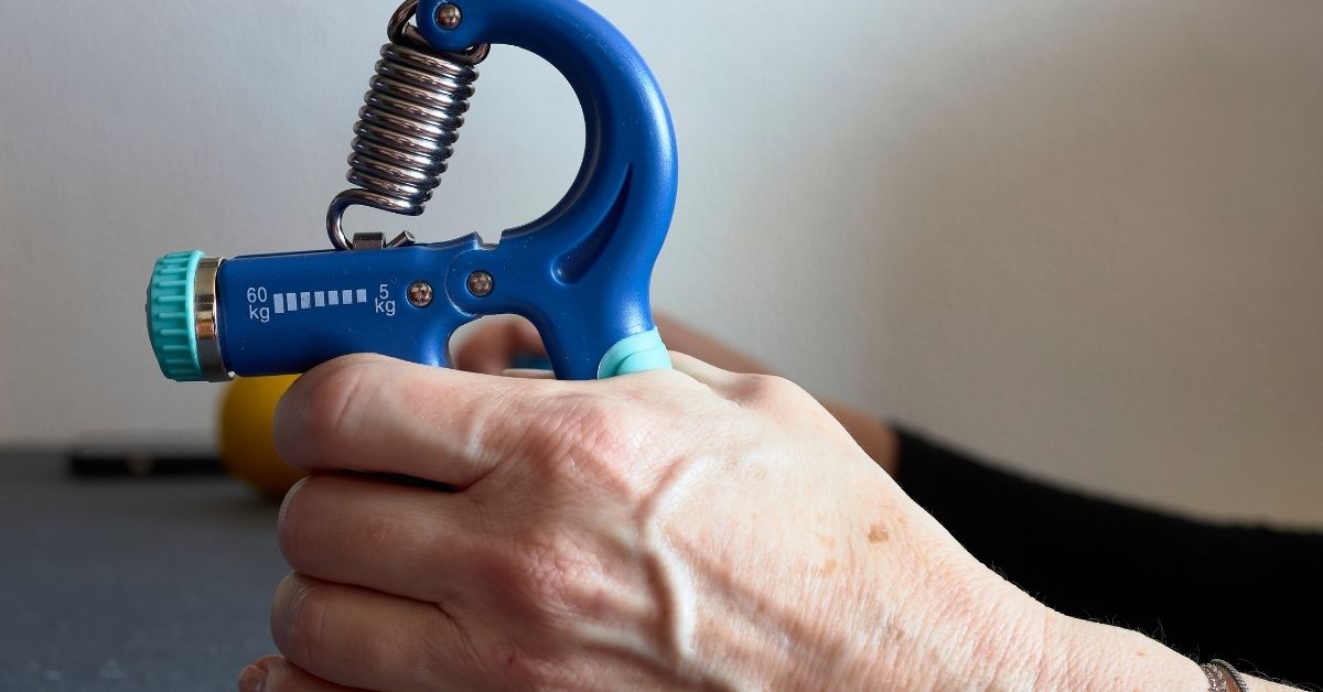 hand-gripper-grip-strength-training-stressfreelongevity Older hand squeezing an adjustable spring hand gripper