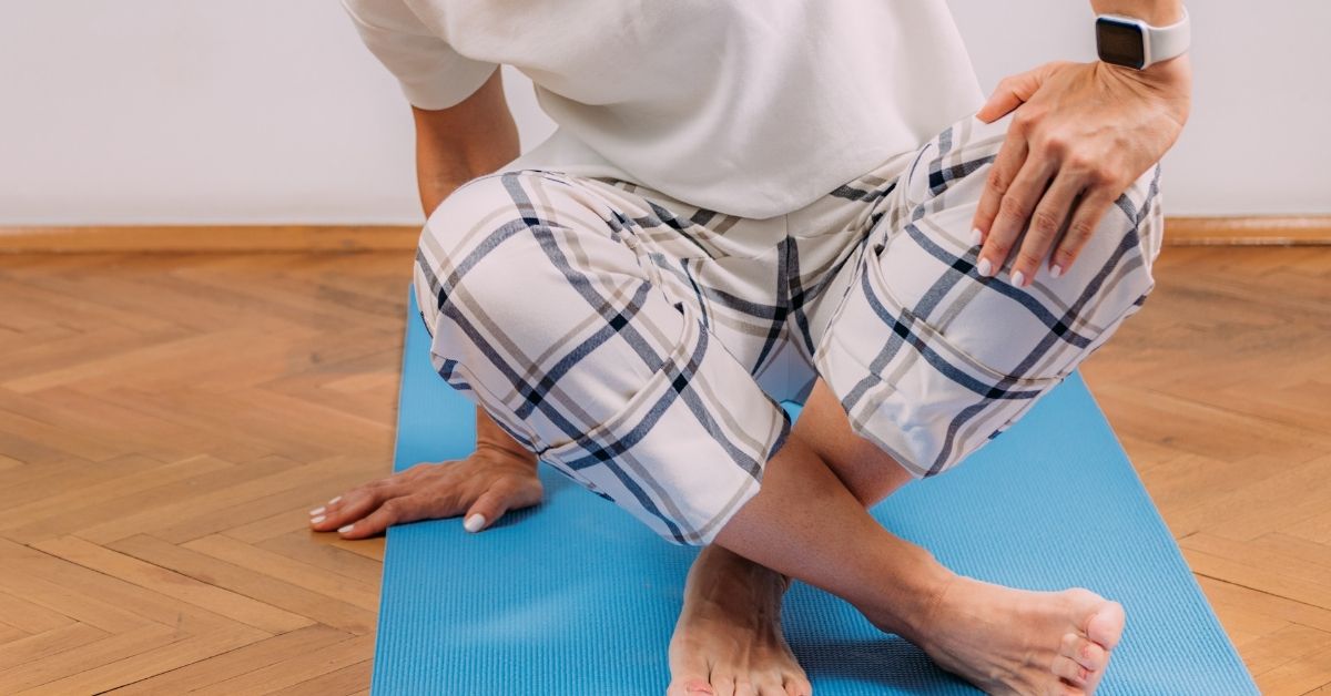 Woman rising from a cross-legged position on the floor with one hand for support, as in the sitting-rising test